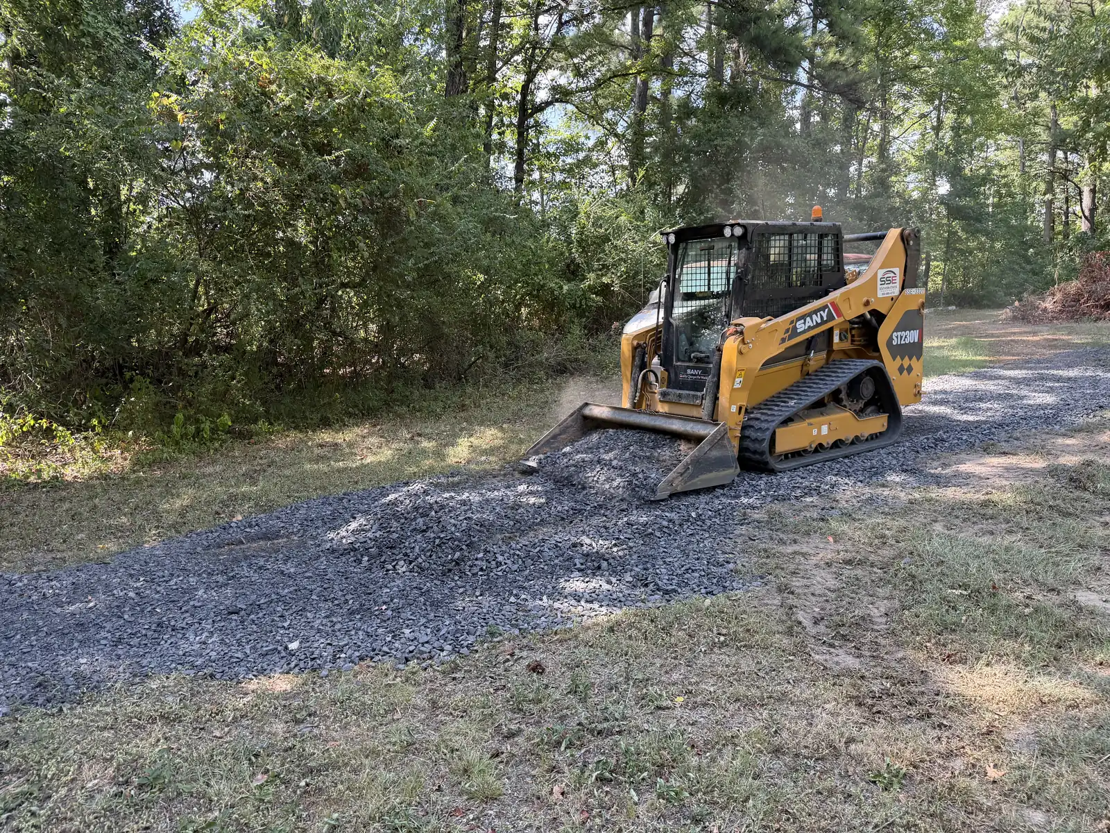 Tracked skid steer placing gravel on a Central Arkansas project site